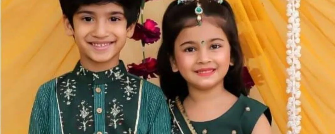 Brother and sister in emerald festive wear, smiling together